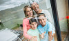 family-of-four-smiling-out-a-window.jpg